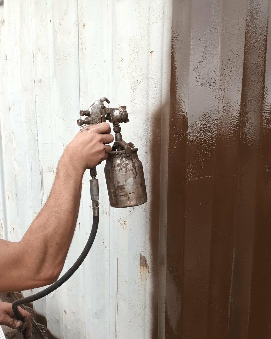 RPS Spraying technician spraying a corrugated panel on site, mid-colour-change from white to brown